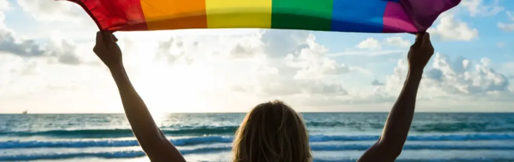 rainbow flag held by a woman's silhouette